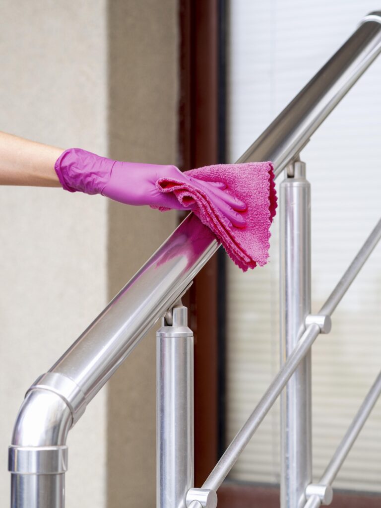 hand with surgical glove cleaning hand rail with cloth